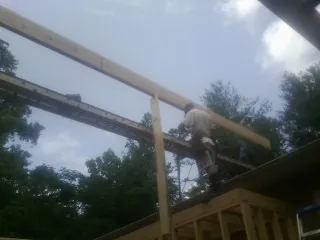 Carpenter setting a ridge beam over a new addition frame — Ice Dam Removal by Roofing Brothers in Velva