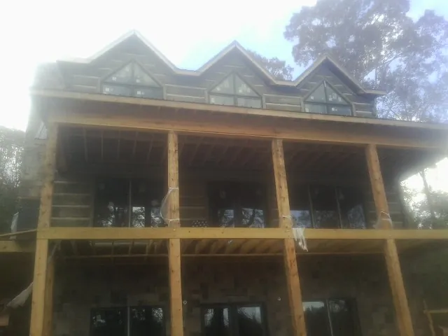 Dormers and porch framing on a large log home under construction — Roof Coating work by our crew in Velva