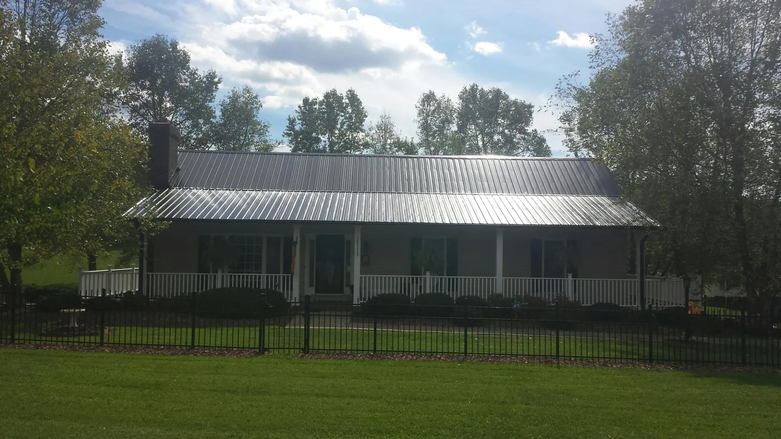Gray metal roof on a brick ranch with a full width front porch — Gutter Guard Installation work by our crew in Velva