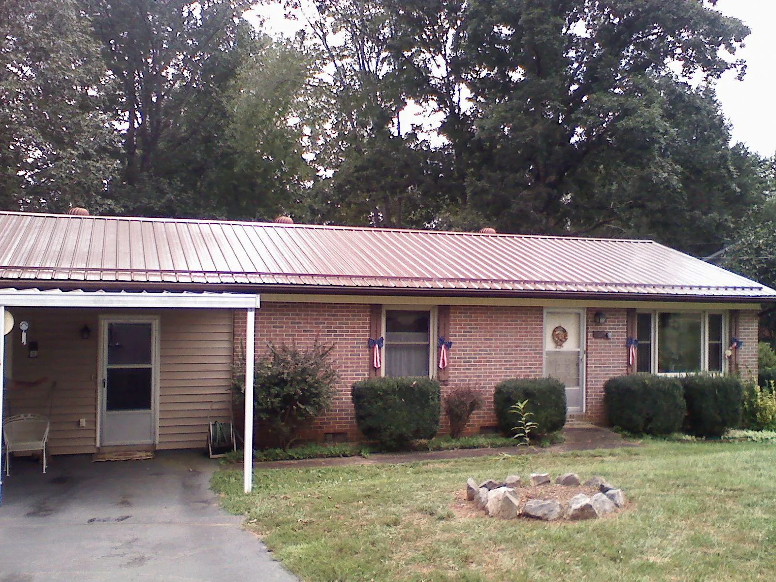 Bronze metal roof and carport on a brick ranch home — Roof Repair work by our crew in Velva